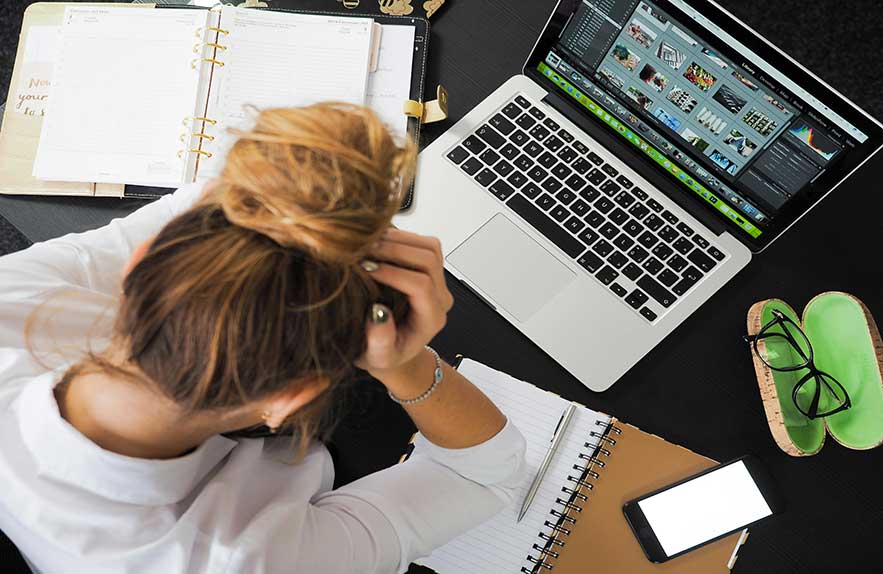 Stressed woman using task management apps and planners at her desk
