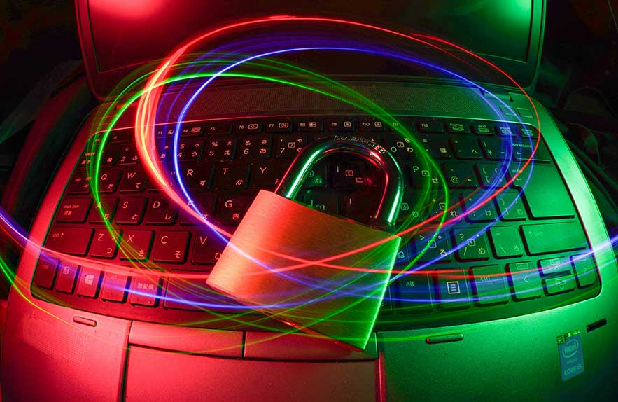 Padlock on laptop keyboard with neon light trails, symbolizing cybersecurity and digital protection